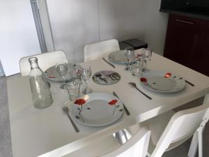 a white table with plates and glasses and a bottle at Le pic epeiche in Saulgé +1 photo