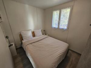 a bedroom with a bed with white sheets and a window at Le pic epeiche in Saulgé