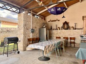 a kitchen with a table and a grill and an umbrella at Le chant du jau in Beaumont