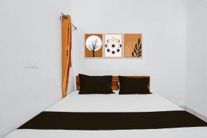 a bedroom with a white bed with black pillows at HOTEL O VIP HILL HOMESTAY in Mājra +22 photos