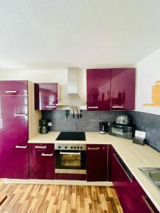 a kitchen with purple cabinets and a stove at Seenland Residenz in Hoyerswerda +36 photos