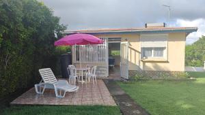 a patio with a table and chairs and an umbrella at Cocooning sur mer Bungalow in Sainte-Anne