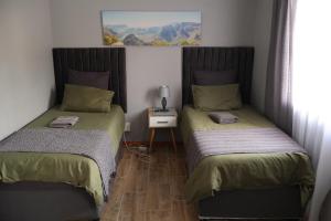 two beds in a small room with a table at FIG TREE HOUSE Entire holiday home, self catering, 4 bedroom, 2 bathroom, deck and garden in Durban