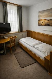 a bedroom with a bed and a desk with a computer at Hotel Ritter in Tuttlingen