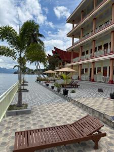 a building with a bench next to the water at Mas Cottages in Tuktuk Siadong