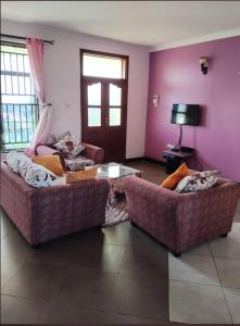 two couches in a living room with purple walls at Greenhome apartment in Poli