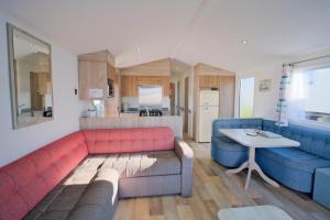 a living room with a red couch and a table at Sirocco Caravan in Westward Ho