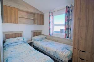 two beds in a small room with a window at Sirocco Caravan in Westward Ho