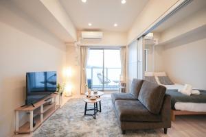 a bedroom with a bed and a couch and a tv at AYA Residence大阪城公園 Osaka Castle JR Morinomiya 徒歩5min in Osaka