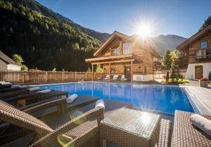 a house with a swimming pool with mountains in the background at Hotel Wiese in Sankt Leonhard im Pitztal