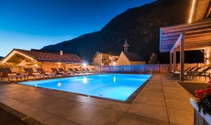 a pool at night with mountains in the background at Hotel Wiese in Sankt Leonhard im Pitztal