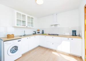 a kitchen with white cabinets and a washer and dryer at Ca na Moli in Artá