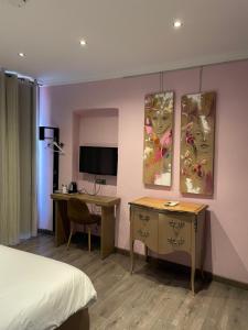 a hotel room with a bed and a desk and a television at Chambre Le Chevalblanc in Ajaccio