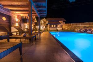 a swimming pool at night with tables and chairs at Hotel Wiese in Sankt Leonhard im Pitztal