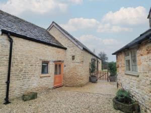 an old brick building with a orange door in a yard at The Forge in Stow on the Wold