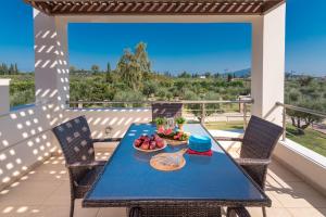 a blue table with a bowl of fruit on a balcony at Astarte Villas - Istar Villa with Tennis Court in Makhairádhon