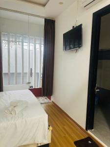 a bedroom with a bed with a flat screen tv on the wall at Full House Hotel Apartment in Danang