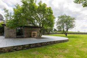 a stone building with a tree in a field at The Studio at Cherry Tree in Natland