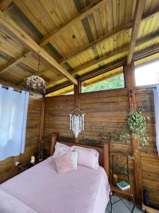 a bedroom with a bed in a wooden room at Chalé Alecrim in Córrego do Bom Jesus