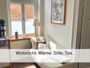 ein Wohnzimmer mit einem Sessel und einem Fenster in der Unterkunft FeWo "Ebbe" im historischen Denkmal, ruhig & modern mit Stil, Kunst und großem Garten, hochwertiger Ausstattung & zentraler Lage in Esens- 3km zur Nordsee, alles fußläufig erreichbar - ideal für Paare oder kleine Familien in Esens