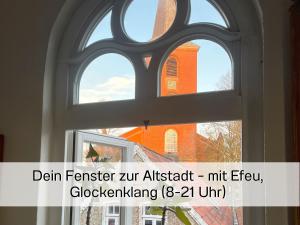 ein Bild eines Fensters mit Blick auf eine Kirche in der Unterkunft FeWo "Ebbe" im historischen Denkmal, ruhig & modern mit Stil, Kunst und großem Garten, hochwertiger Ausstattung & zentraler Lage in Esens- 3km zur Nordsee, alles fußläufig erreichbar - ideal für Paare oder kleine Familien in Esens