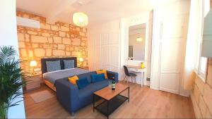 a room with a bed and a blue couch and a table at Hôtes de Saint Emilion in Saint-Émilion