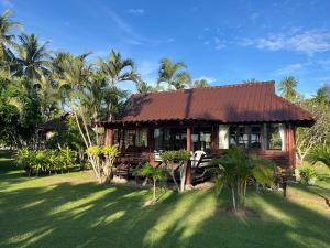 a house with a brown roof on a grass field at Suan Bankrut Beach Resort in Ban Krut