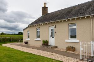 a house with a white door and a grass yard at Bachilton Farm Holidays in Perth