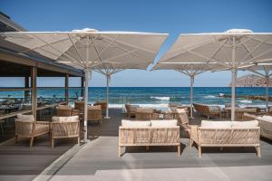 a restaurant with chairs and umbrellas on the beach at Porto Platanias Beach Luxury Selection - Adults Only in Platanias
