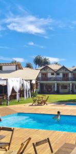 a villa with a swimming pool in front of a house at Pousada Real Cipo in Serra do Cipo