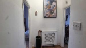 a white room with a painting on the wall and a fireplace at Extra Large One Bedroom Flat with Parking in London