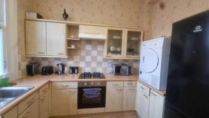 a kitchen with wooden cabinets and a black refrigerator at Extra Large One Bedroom Flat with Parking in London