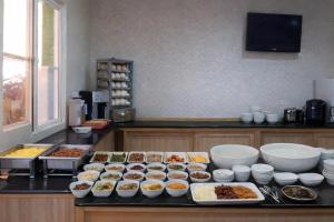 a kitchen with a counter with many bowls of food at Huaxiang Motel - Daliao in Daliao