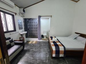 a bedroom with a bed and a couch and a bathroom at Seromue in Antsiranana