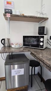 a kitchen with a counter with a microwave and a stool at Sleep@161 Benade Drive in Bloemfontein +9 photos