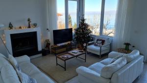 a living room with white furniture and a christmas tree at The Lakeview Cottage near Shiroka center in Shirokë