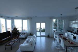 a living room with white furniture and a christmas tree at The Lakeview Cottage near Shiroka center in Shirokë
