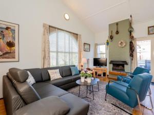 a living room with a brown couch and blue chairs at Christoffellaan 57 in Brouwershaven