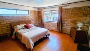 a bedroom with a bed and a brick wall at Casa Quinta el Labrador Renaico in Estación Roblería