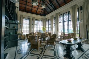 a dining room with a table and chairs and windows at Seashell Samssara Havelock in Havelock Island