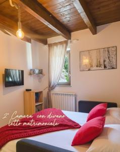 a bedroom with a bed with red pillows and a window at Attico e super attico panoramico in Rocca di Cambio