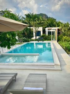 a swimming pool with two benches next to a house at Zana Villas in Krabi