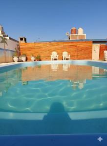 a swimming pool with two white chairs in the background at Cabañas los Materos 3 in Santa María +5 photos