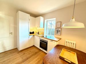 a kitchen with white cabinets and a wooden table at Ferienhaus 1 Fuchsweg in Stralsund