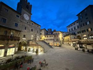 a group of people sitting in a courtyard with a clock tower at La Casa sulla Piazza in Cortona