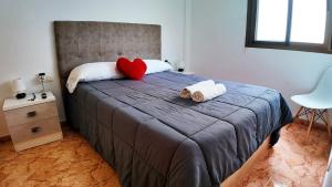 a bed with a red heart pillow and two towels at Apartalux Zen Pacific in El Cabo de Gata