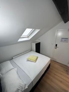 a white bedroom with a bed with a skylight at Hotel Albert in Brussels