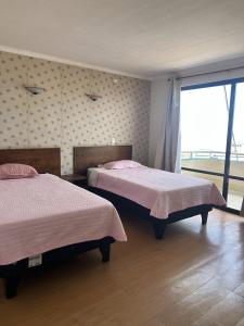 a bedroom with two beds and a large window at Hotel Capri in Iquique