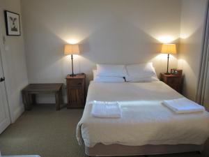 a bedroom with a large white bed with two lamps at The Playhouse Hotel in Barraba