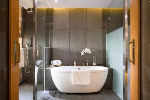 a bathroom with a white tub and a shower at Baymond Hotel in Busan